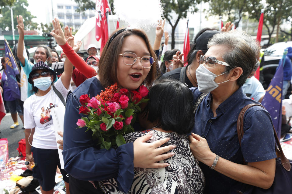 A pro-democracy activist, Panusaya Sithijirawattanakul, front left, receives a flower from her supporter as she arrived at the Attorney General office in Bangkok, Thailand, Monday, March 8, 2021. Prosecutors in Thailand charged 18 pro-democracy activists with sedition on Monday, while lodging additional charges of insulting the monarchy against three of them. (AP Photo/Sakchai Lalit)