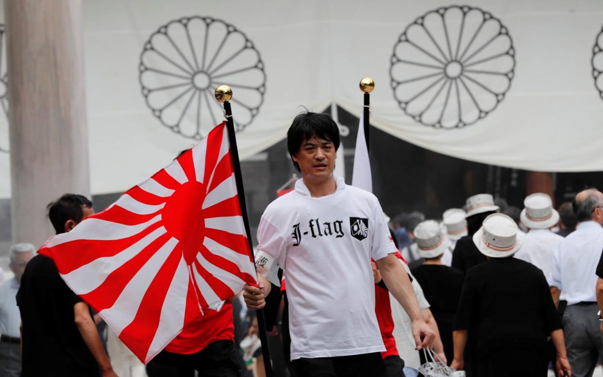 A man holds an imperial flag as he visits the Yasukuni Shrine in Tokyo in August on the 74th anniversary of Japan's surrender in World War Two - REUTERS