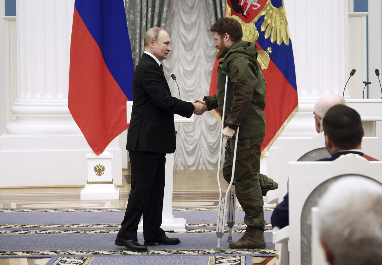 Russian President Vladimir Putin, left, awards founder of the WarGonzo media project Semyon Pegov with the Order of Courage during an awarding ceremony at the Kremlin's St. Catherine Hall in Moscow, Russia, Tuesday, Dec. 20, 2022. (Valeriy Sharifulin, Sputnik, Kremlin Pool Photo via AP)