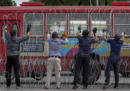 Men make barricades with buses, concreate blocks and barbed wires blocking a road heading to the Government House, office of the prime minister, ahead of a pro-democracy street march and a rally in Bangkok, Thailand Sunday, Nov. 8, 2020. (AP Photo/Rapeephat Sitichailapa)