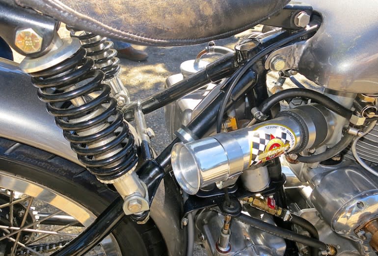 Bicycle shocks provide the rear suspension. Oil tank moved to the left to make room for the intake tract, which puts the bell mouth 13 inches from the valve face, good for a bump of 6 hp. Larger carb has a 380 main jet, opposed to the original 190.