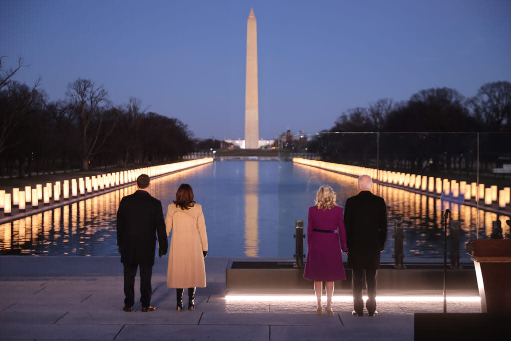 (L-R) Douglas Emhoff, U.S. Vice President-elect Kamala Harris, Dr. Jill Biden and U.S. President-elect Joe Biden look down the National Mall as lamps are lit to honor the nearly 400,000 American victims of the coronavirus pandemic at the Lincoln Memorial Reflecting Pool January 19, 2021 in Washington, DC. (Photo by Chip Somodevilla/Getty Images)