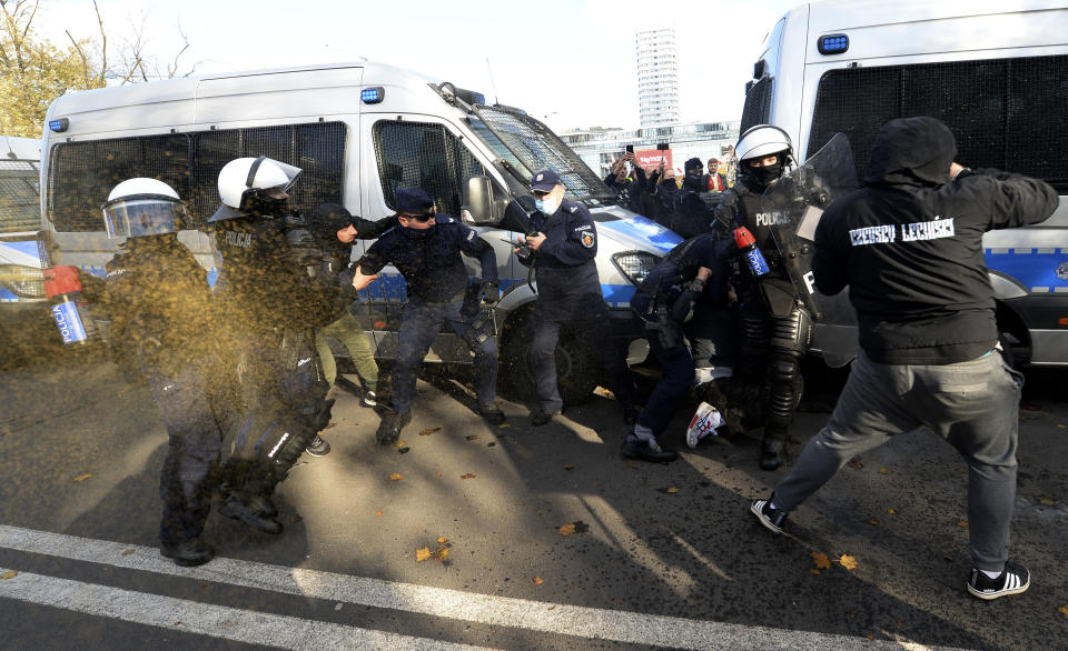 Polish police aim tear gas cannisters at protesters angry over new restrictions aimed at fighting the coronavirus pandemic, in Warsaw, Poland, Saturday, Oct. 24, 2020. The protesters included entrepreneurs, far-right politicians, football fans and vaccine opponents. The protesters, many wearing no protective masks, violated a new restriction on gatherings of more people. The clashes come amid rising social tensions and as new restrictions just short of a full lockdown took effect Saturday. (AP Photo/Czarek Sokolowski)