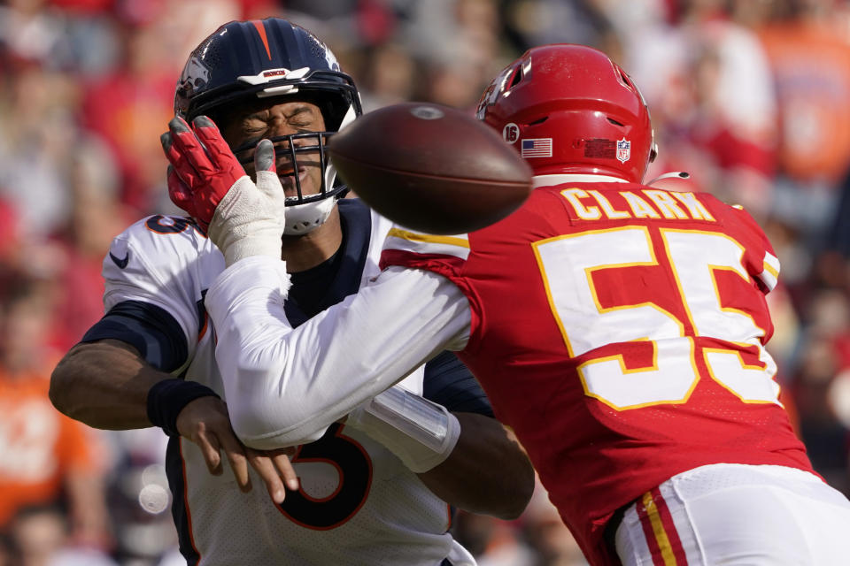 Denver Broncos quarterback Russell Wilson, left, is hit by Kansas City Chiefs defensive end Frank Clark (55) while throwing during the first half of an NFL football game Sunday, Jan. 1, 2023, in Kansas City, Mo. (AP Photo/Ed Zurga)