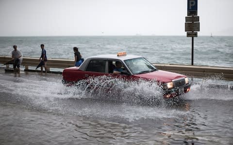 A taxi drives on a flooded street as typhoon Hato passes Hong Kong, - Credit: EPA