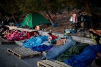 FILE PHOTO: Two children eat cookies as refugees and migrants from the destroyed Moria camp sleep on the side of a road, on the island of Lesbos