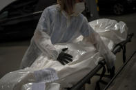 Mortuary worker Marina Gómez handles the body of a person who died of COVID-19 at Mémora morgue in Barcelona, Spain, Monday, Nov. 16, 2020. Gómez and her fellow mortuary workers form part of Spain's rarely seen front line in the fight against COVID-19. Like doctors and nurses, they are part of a group of essential workers who see and touch the daily march of death amid the worst public health crisis in over a century. (AP Photo/Emilio Morenatti)