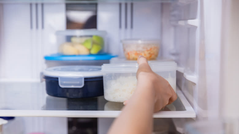 Hand pulling leftovers from fridge 