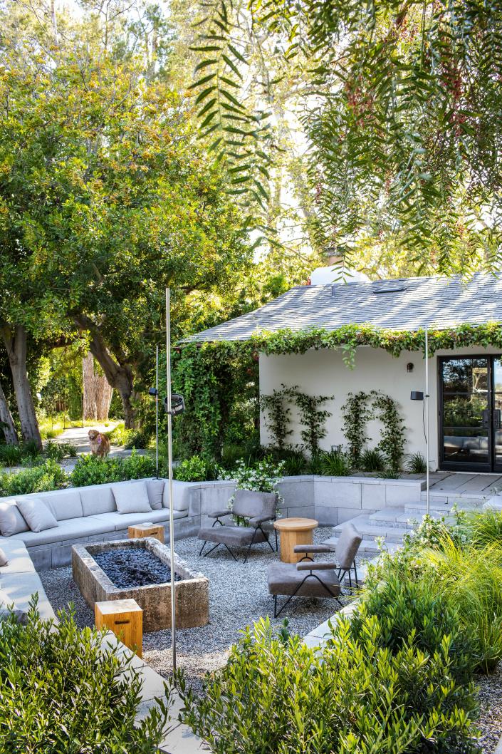 A sunken back yard with a cozy sectional and firepit.