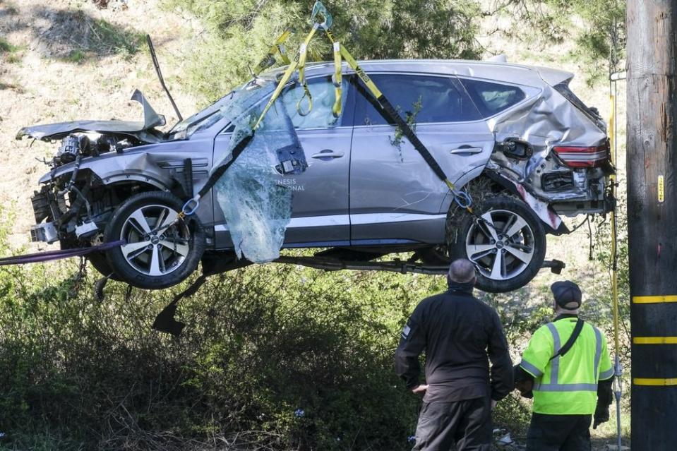 A crane is used to lift a vehicle following a rollover accident involving golfer Tiger Woods, Tuesday, Feb. 23, 2021, in the Rancho Palos Verdes suburb of Los Angeles. (AP Photo/Ringo H.W. Chiu)