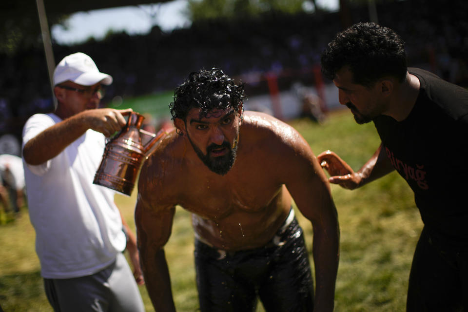 A wrestler is doused in oil by an 'oiler', during the 661st annual Historic Kirkpinar Oil Wrestling championship, in Edirne, northwestern Turkey, Saturday, July 2, 2022. The festival is part of UNESCO's List of Intangible Cultural Heritages. (AP Photo/Francisco Seco)