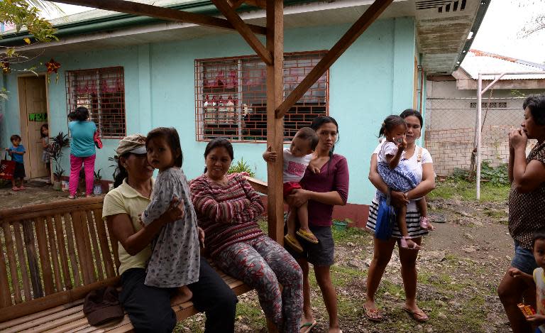 Mothers accompany their children to a day care center, next to the now abandoned house (back) that used to streamed live sex acts of children to paedophiles around the world, in Ibabao village, Cebu provnce, in central Philippines on January 21, 2014