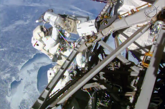 Expedition 42 spacewalker Terry Virts configures a newly-installed antenna boom as Butch Wilmore routes cables outside the International Space Station on March 1, 2015.