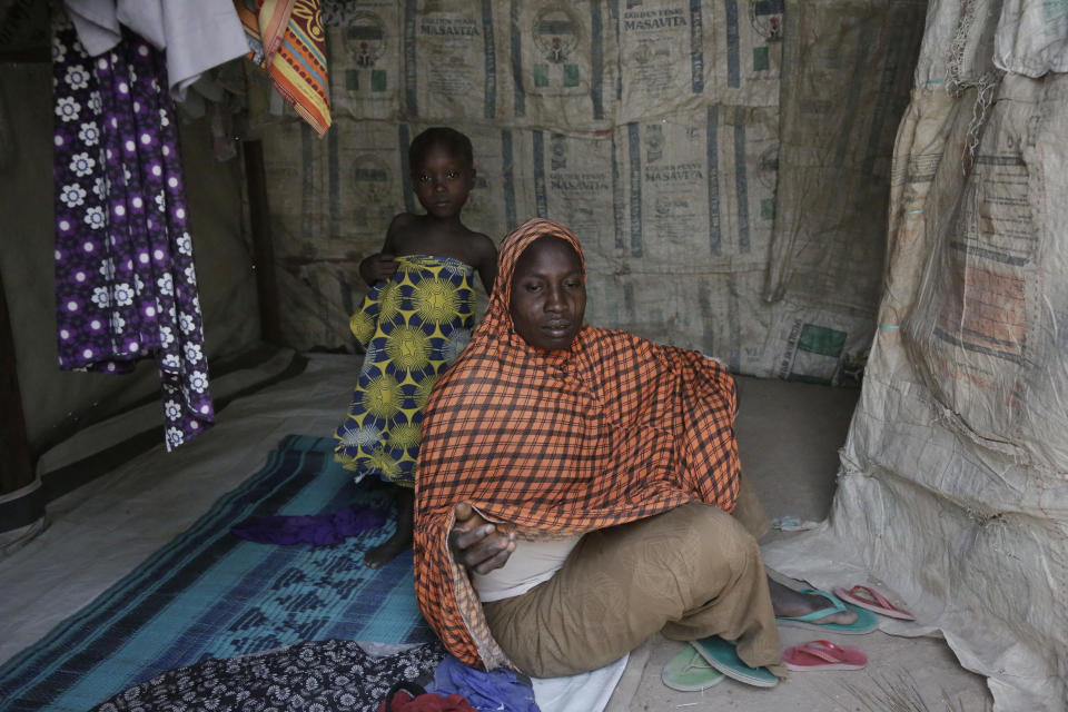 In this photo taken on Monday, Feb. 18, 2019, Fati Umar, a woman displaced by Islamist extremist sits inside her room with her daughter at Malkohi camp in Yola, Nigeria. Fati Umar of Gwoza, said she was unable to bury her husband after fleeing a 2014 Boko Haram attack that came while she was cultivating her garden, and for days she hid in the bush with her children. Fati speaks in the makeshift camp for internally displaced people that she shares with hundreds who all have their own story to tell, and who all have more important issues than the upcoming presidential election. (AP Photo/ Sunday Alamba)