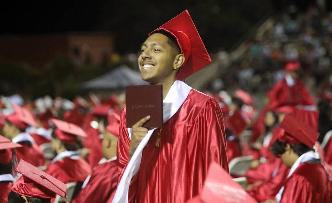 A graduate holds up his diploma during the McLane High graduation at the school stadium on June 6, 2023.