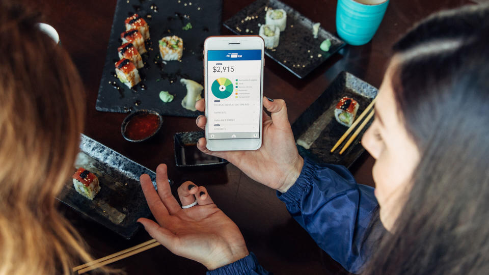 Two women of the Millennial Generation are looking at a financial statement while eating lunch at a local sushi restaurant.