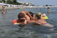 A couple enjoy the beach in the Black Sea resort of Sochi, Russia, Sunday, July 5, 2020. Tens of thousands of vacation-goers in Russia and Ukraine have descended on Black Sea beaches, paying little attention to safety measures despite levels of contagion still remaining high in both countries. (AP Photo/Artur Lebedev)