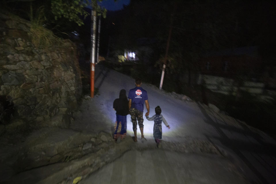 A man walks holding the hands of two children at dusk at Dardkhor village, where several cases of wild animals attacking villagers have been reported, outskirts of Srinagar, Indian controlled Kashmir, Monday, Aug. 24, 2020. Amid the long-raging deadly strife in Indian-controlled Kashmir, another conflict is silently taking its toll on the Himalayan region’s residents: the conflict between man and wild animals. According to official data, at least 67 people have been killed and 940 others injured in the past five years in attacks by wild animals in the famed Kashmir Valley, a vast collection of alpine forests, connected wetlands and waterways known as much for its idyllic vistas as for its decades-long armed conflict between Indian troops and rebels. (AP Photo/Mukhtar Khan)
