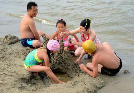 A family builds a sandcastle at Songdowon International Children's Camp in Wonsan City in this undated photo released by KCNA. KCNA/via REUTERS