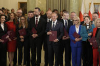 The new Polish Prime Minister Donald Tusk, centre, with members of his government posses for cameras at the presidential palace in Warsaw, Poland, Wednesday, Dec. 13, 2023. Donald Tusk was sworn in by the president in a ceremony where each of his ministers was also taking the oath of office. (AP Photo/Czarek Sokolowski)