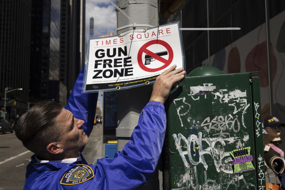 An New York Police Department Public Affairs officer sets up signs reading Gun Free Zone around Times Square, Wednesday, Aug. 31, 2022, in New York. (AP Photo/Yuki Iwamura)