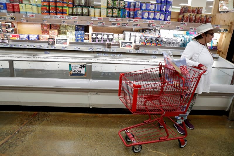 A woman stands with an empty shopping cart, prior to California's Governor Gavin Newsom's effective immediately statewide "stay at home order”, in the face of the fast-spreading pandemic coronavirus (COVID-19), at Trader Joe’s in Napa, California