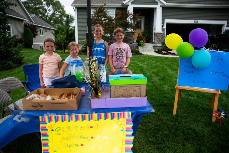 From left to right: Everley DeWitt, Blakely Sloop, Penny DeWitt and Adeline Sloop stand for a photo as they run a lemonade stand for the Children's Advocacy Center on Friday, Aug. 5, 2022, in Holland.