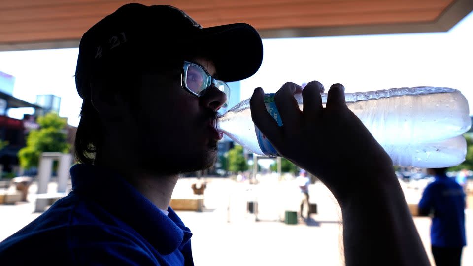 Texas resident drinks water while working security outside in Arlington, Texas, on Monday. - LM Otero/AP