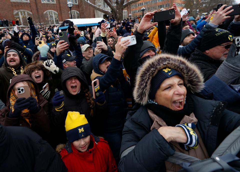 Michigan fans yell and cheer as the Michigan football team and newly crowned national champions come down South University Avenue towards South State Street in pickup trucks and old fire trucks during a parade on campus in Ann Arbor on Saturday, Jan. 13, 2024.