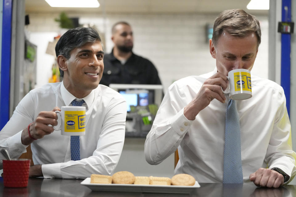 Britain's Prime Minister Rishi Sunak (L), with Britain's Chancellor of the Exchequer Jeremy Hunt (R) have drink and biscuits with employees during a visit to a builders warehouse in London on March 6, 2024. Britain's embattled Conservative government on Wednesday announced a fresh tax cut for millions of workers to woo voters before a general election expected this year. (Photo by Kirsty Wigglesworth / POOL / AFP) (Photo by KIRSTY WIGGLESWORTH/POOL/AFP via Getty Images)