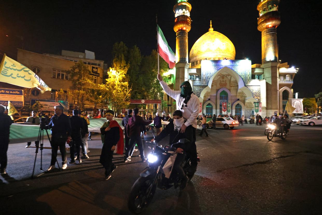 Demonstrators wave Iran's flag as they gather at Palestine Square in Tehran on April 14, 2024, after Iran launched a drone and missile attack on Israel. Iran's Revolutionary Guards confirmed early April 14, 2024 that a drone and missile attack was under way against Israel in retaliation for a deadly April 1 drone strike on its Damascus consulate.