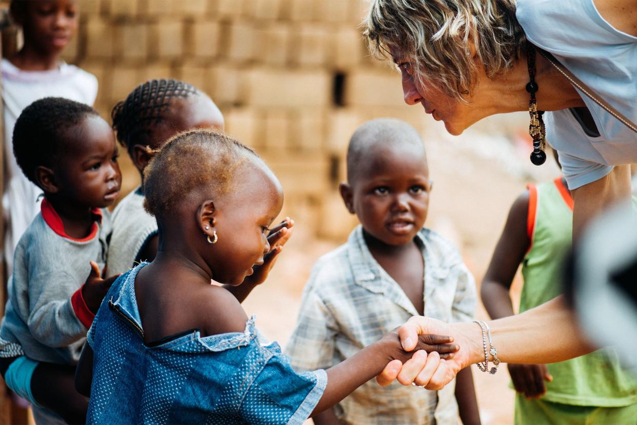 Caucasian woman shaking hands with African children