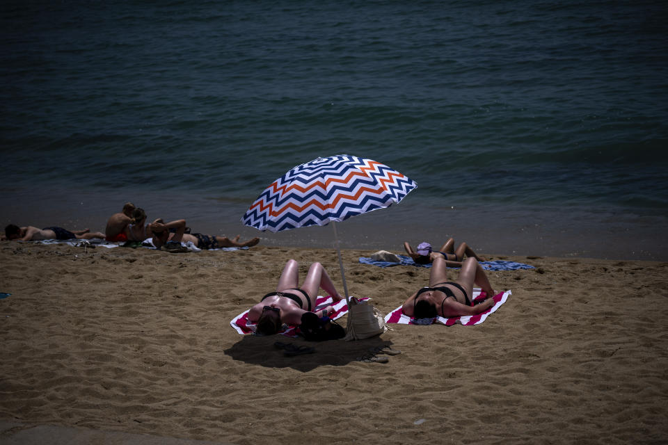 People sunbathe on a beach in Barcelona, Spain, Monday, July 17, 2023. Spain's Aemet weather agency said a heatwave starting Monday "will affect a large part of the countries bordering the Mediterranean" with temperatures in some southern areas of Spain exceeding 42-44 ºC. (AP Photo/Emilio Morenatti)