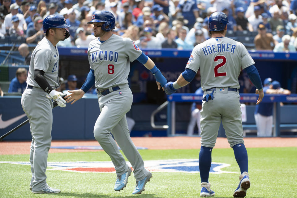 Chicago Cubs' Ian Happ (8), Nico Hoerner (2) and Seiya Suzuki (27) celebrate after Happ and Hoerner scored off a double by Dansby Swanson against the Toronto Blue Jays in the first inning of a baseball game in Toronto, Sunday, Aug. 13, 2023. (Jon Blacker/The Canadian Press via AP)