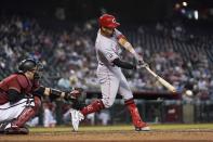 Cincinnati Reds' Eugenio Suarez, right, gets a broken-bat single to break up a no-hit bid by Arizona Diamondbacks starting pitcher Luke Weaver as Diamondbacks catcher Carson Kelly, left, reaches with his glove during the seventh inning of a baseball game Sunday, April 11, 2021, in Phoenix. (AP Photo/Ross D. Franklin)