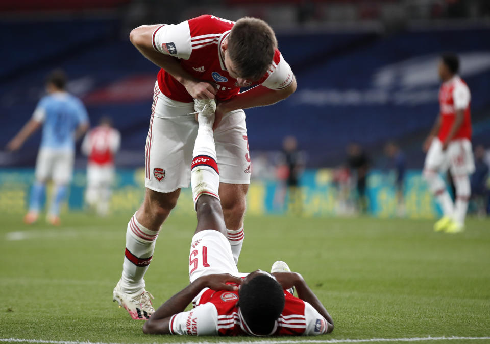 Arsenal's Kieran Tierney helps teammate Ainsley Maitland-Niles with cramp during the FA Cup semifinal soccer match between Arsenal and Manchester City at Wembley in London, England, Saturday, July 18, 2020. (AP Photo/Matt Childs,Pool)