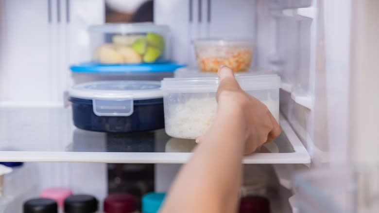 hand placing container in refrigerator
