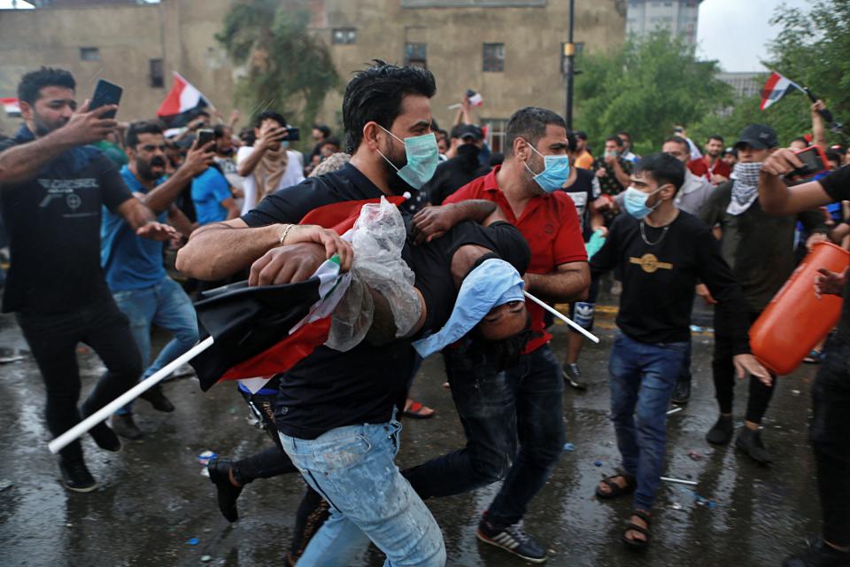 An injured protestor is rushed to a hospital during a demonstration in central Baghdad, Iraq, Friday, Oct. 25, 2019. Iraqi police fired live shots into the air as well as rubber bullets and dozens of tear gas canisters on Friday to disperse thousands of protesters on the streets of Baghdad, sending young demonstrators running for cover and enveloping a main bridge in the capital with thick white smoke. (AP Photo/Khalid Mohammed)