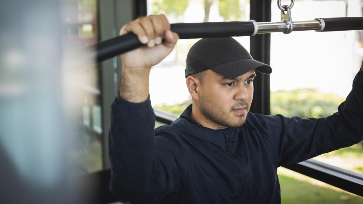  Man performs lat pull-down. 