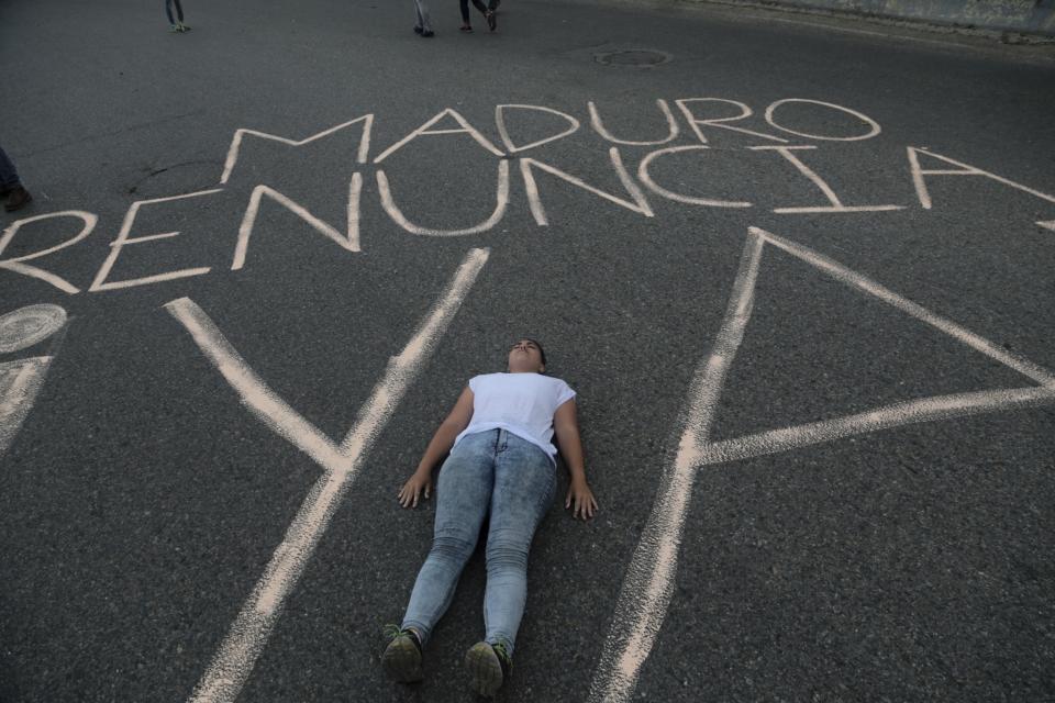 <p>A woman lies in the middle of the street covered with the Spanish message “Maduro, resign already” during an opposition sit-in, in Caracas, Venezuela, Monday, May 15, 2017. (AP Photo/Fernando Llano) </p>