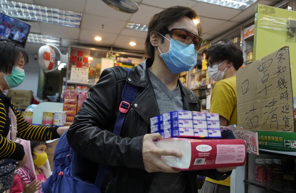 Un hombre porta una mascarilla mientras carga pañuelos de papel que compró en una farmacia de Hong Kong, el jueves 6 de febrero de 2020. (AP Foto/Vincent Yu)