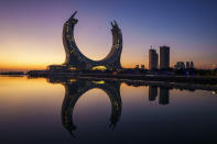 A plane flies over the Crescent Tower Lusail during sunrise in Lusail, Qatar, Thursday, Nov. 24, 2022. (AP Photo/Pavel Golovkin)