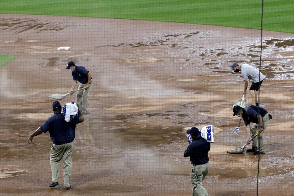 Grounds crew members work on the rain-soaked field during the 10th inning of a baseball game between the Cleveland Indians and the Chicago White Sox on Sunday, Aug. 9, 2020, in Chicago. (AP Photo/Nam Y. Huh)