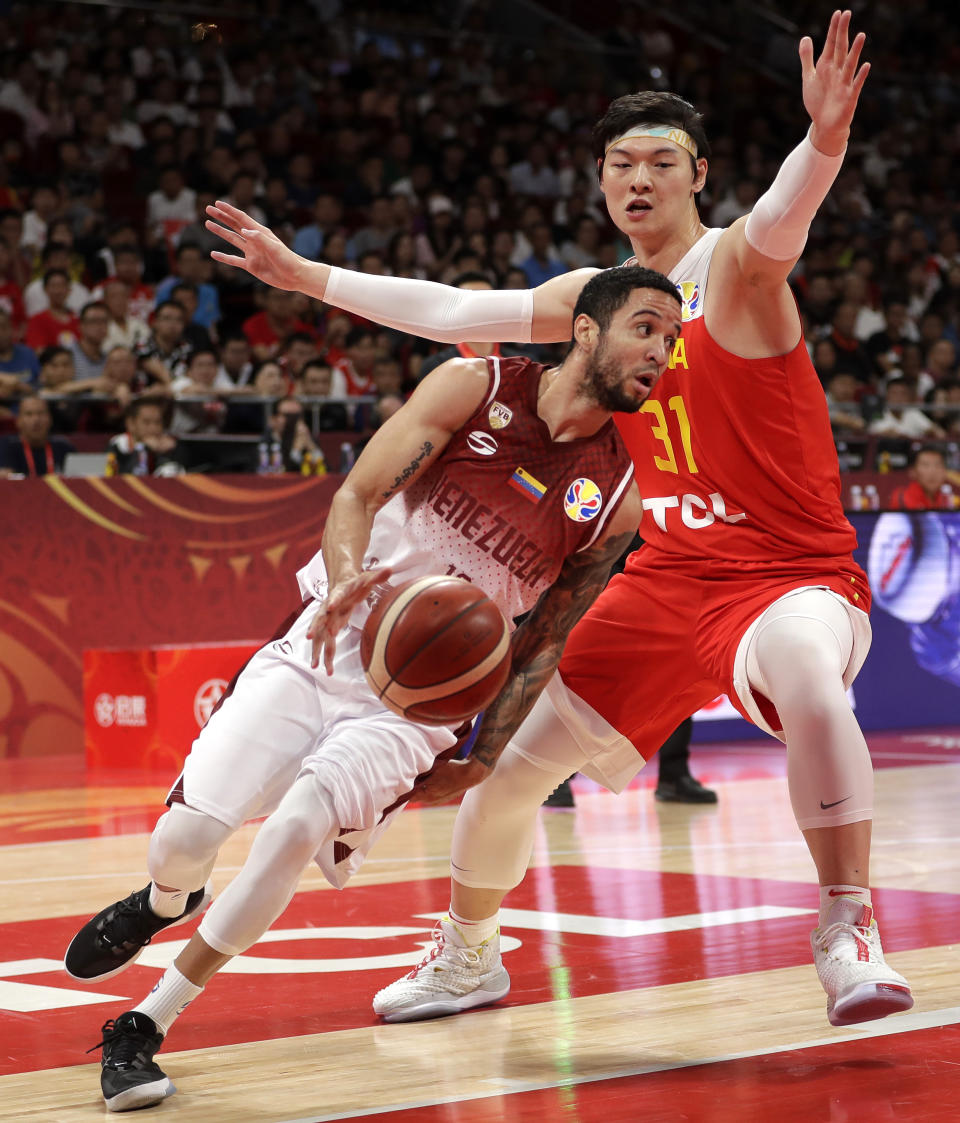 Heissler Guillent of Venezuela drives past Wang Zhelin of China during their group phase game in the FIBA Basketball World Cup at the Cadillac Arena in Beijing, Wednesday, Sept. 4, 2019. (AP Photo/Mark Schiefelbein)