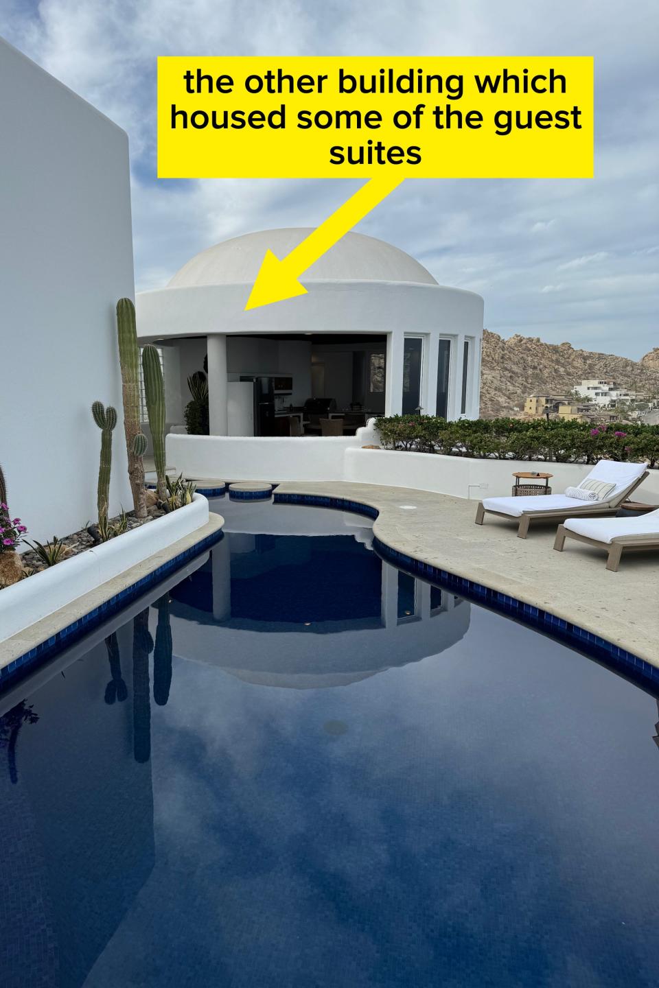 Luxury villa with a private pool and lounge chairs, surrounded by cacti, offering a scenic desert landscape view in the background