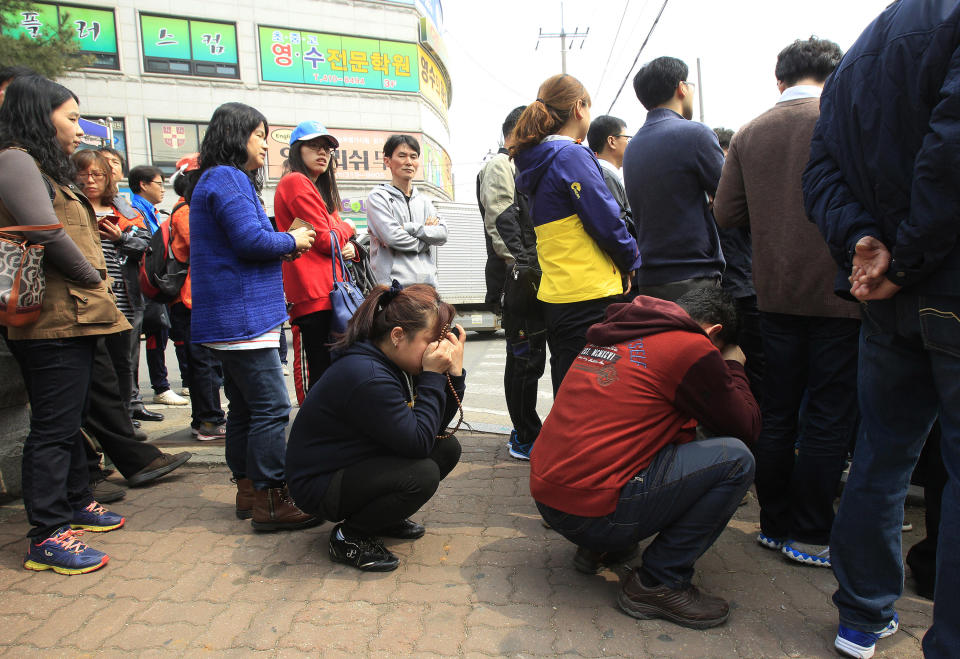 Parents wait for a bus to meet with their children rescued from a ferry that sank off the country's southern coast, at Danwon high school in Ansan, South Korea, Wednesday, April 16, 2014. Dozens of boats, helicopters and divers scrambled to rescue more than 470 people, including 325 students on a school trip from the high school, after the ferry sank earlier in the day. (AP Photo/Ahn Young-joon)