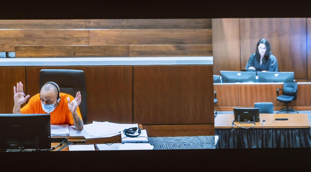 Darrell Brooks gestures as he appears via video from an adjacent courtroom after being removed by Waukesha County Circuit Court Judge Jennifer Dorow, on screen to the right, for repeated interruptions in a Waukesha County Circuit Court during the third day of his trial in Waukesha, Wis., Wednesday, Oct. 5, 2022. Brooks, who is representing himself during the trial, is accused of killing six people and injuring dozens more when he allegedly drove his SUV through a Christmas parade in Wisconsin last year. (Scott Ash/Milwaukee Journal-Sentinel via AP, Pool)