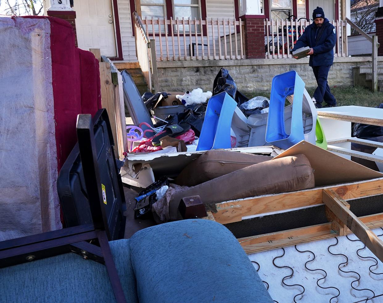 December 1, 2022; Columbus, Ohio; City of Columbus solid waste investigator Bryan White inspects the front yard of a duplex (seen behind him) on Republic Ave. where the contents of the residence (front door at far left) were placed outside.  Fred Squillante-The Columbus Dispatch