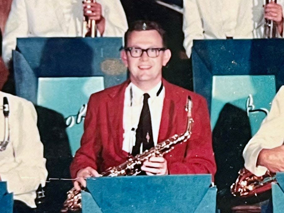 A saxophonist wearing a red jacket performing in a band