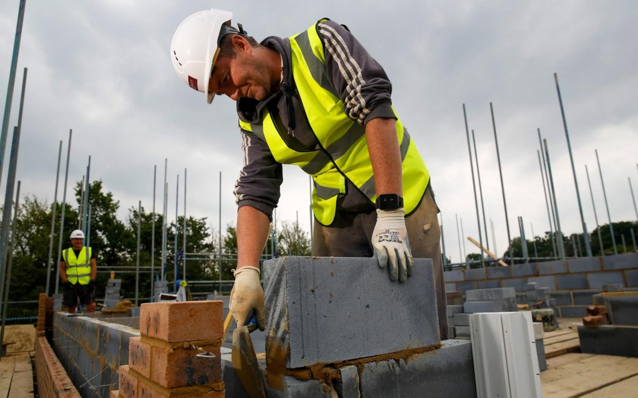 A bricklayer, wearing technology which vibrates when he breaches social distancing guidelines, on a residential construction site near Farnborough - Luke MacGregor /Bloomberg